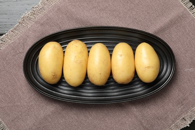 Photo of Fresh raw potatoes on wooden table, top view