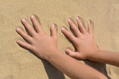 Photo of Child leaving handprints on sand outdoors, closeup. Fleeting time concept