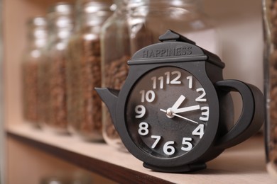 Photo of Teapot shaped clock on shelf with jars of coffee beans
