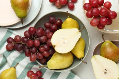 Fresh ripe pears and grapes on light grey table, flat lay