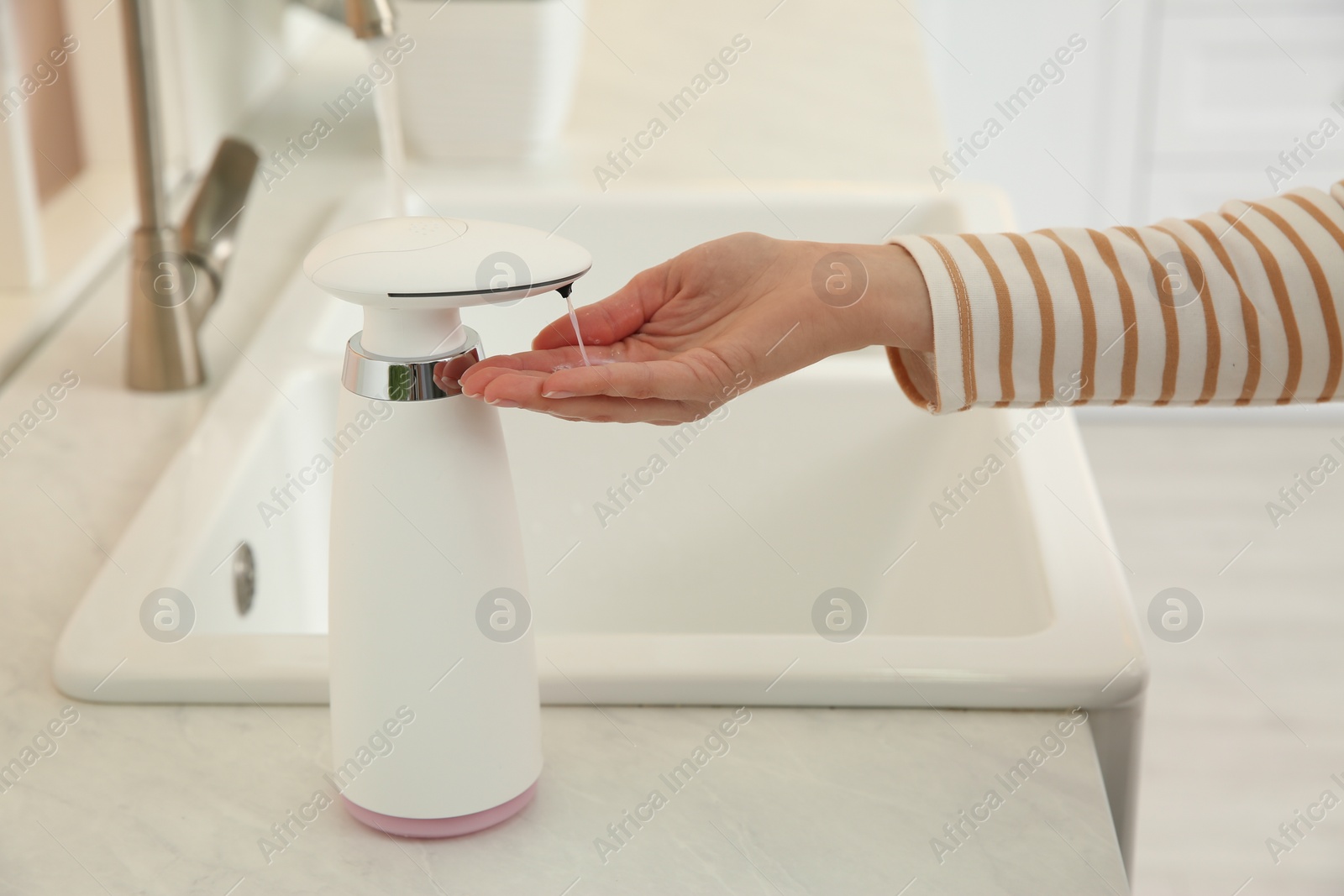 Photo of Woman using automatic soap dispenser in kitchen, closeup