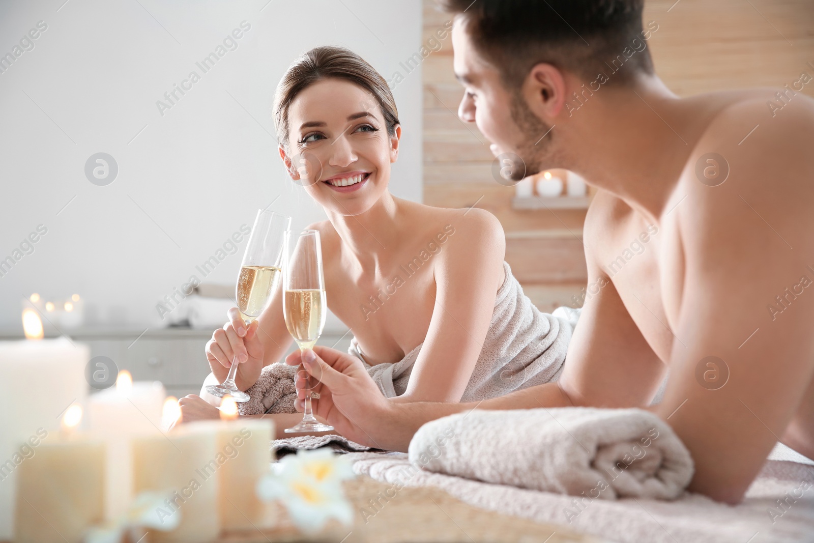Photo of Romantic young couple with champagne in spa salon