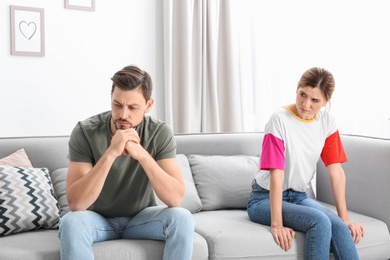 Photo of Couple ignoring each other after argument in living room. Relationship problems