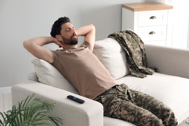 Photo of Soldier napping on soft sofa in living room. Military service