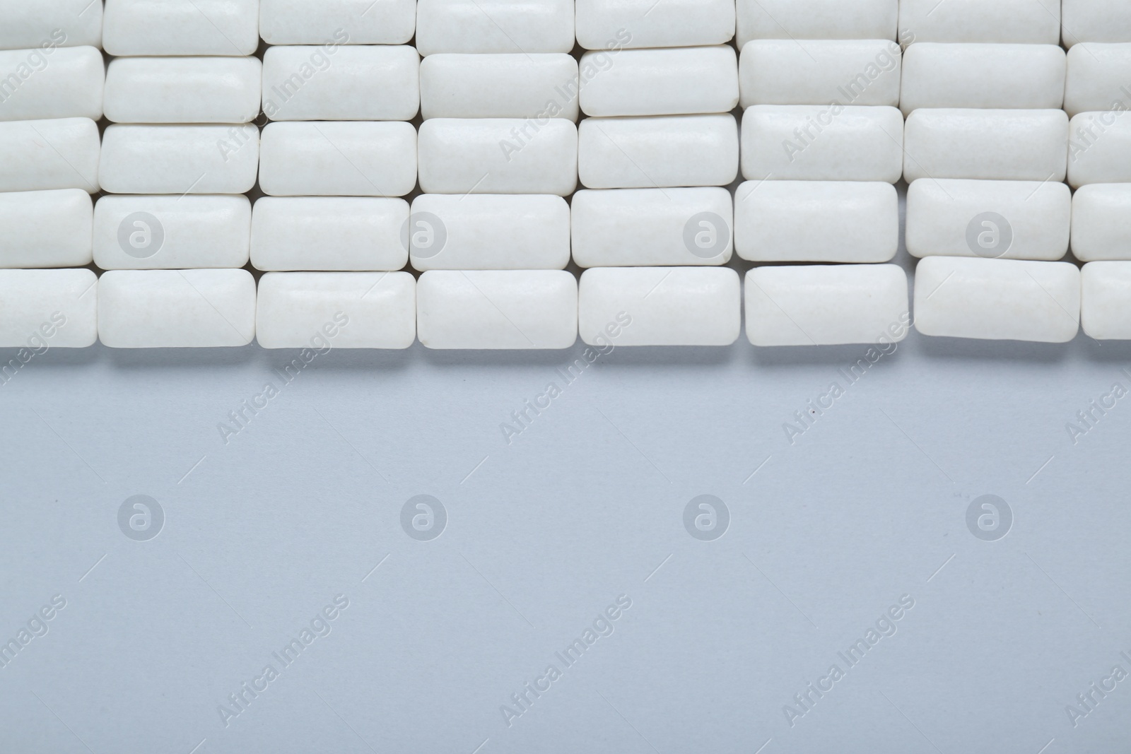 Photo of Tasty white chewing gums on light grey background, flat lay. Space for text