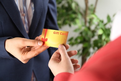 Photo of Women with gift card on blurred background, closeup 