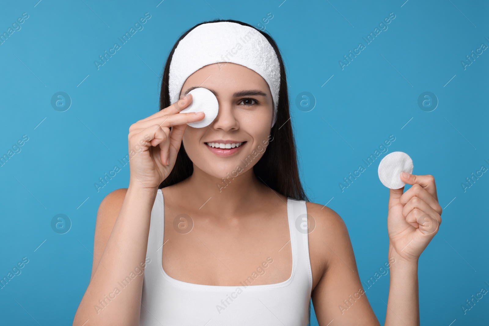 Photo of Young woman with cotton pads on light blue background