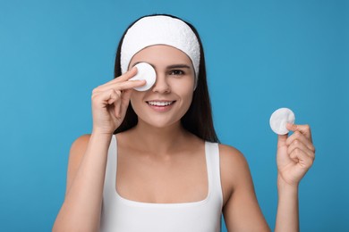 Young woman with cotton pads on light blue background