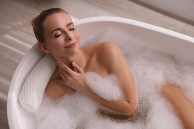 Photo of Beautiful woman taking bath in tub with foam indoors, top view