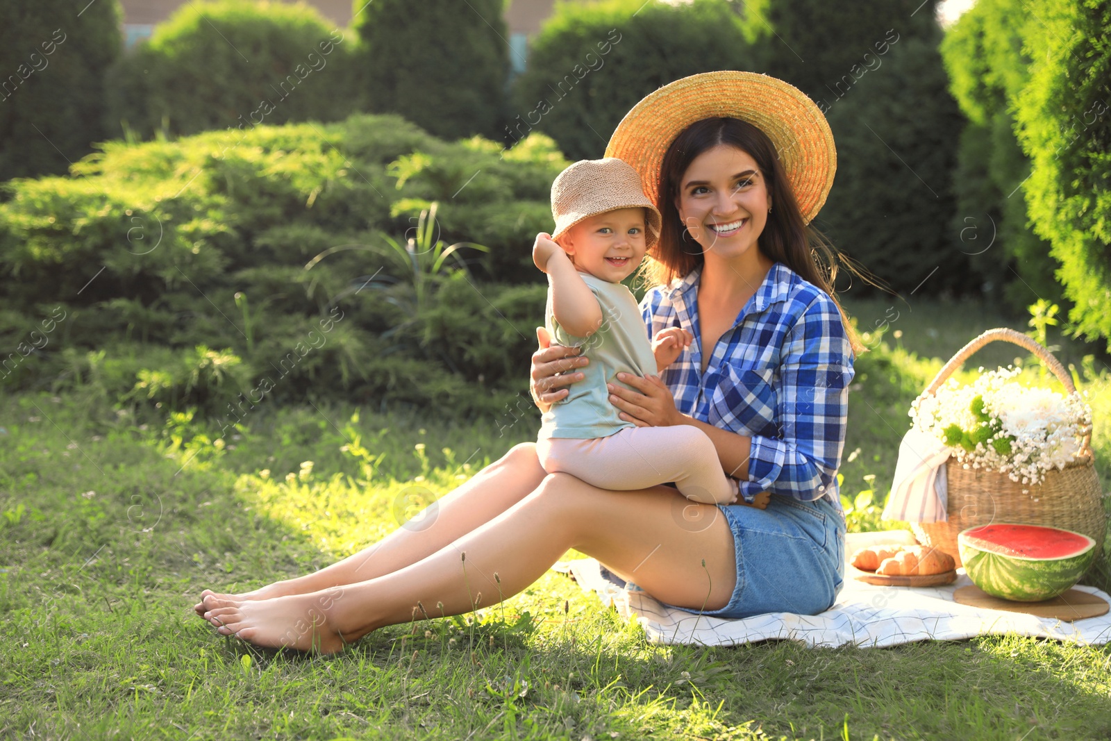 Photo of Mother with her baby daughter having picnic in garden on sunny day