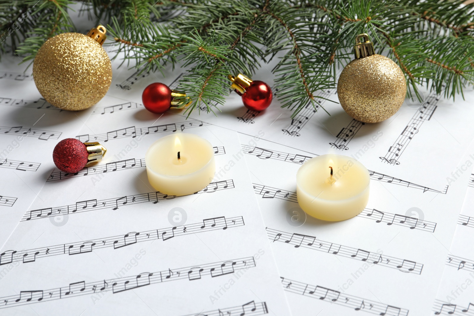 Photo of Composition with Christmas decorations and candles on music sheets