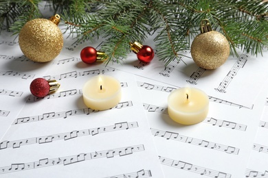 Composition with Christmas decorations and candles on music sheets