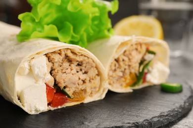 Delicious tortilla wraps with tuna on grey table, closeup. Space for text
