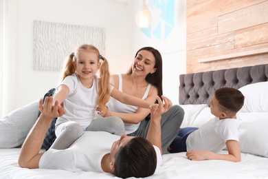 Photo of Happy young family together on large bed