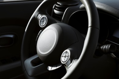 Black steering wheel inside of modern car, closeup