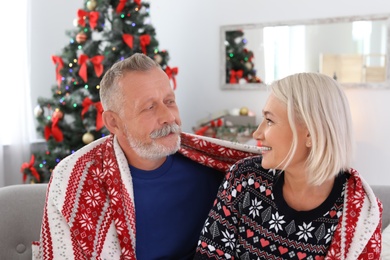 Happy mature couple with plaid at home. Christmas celebration