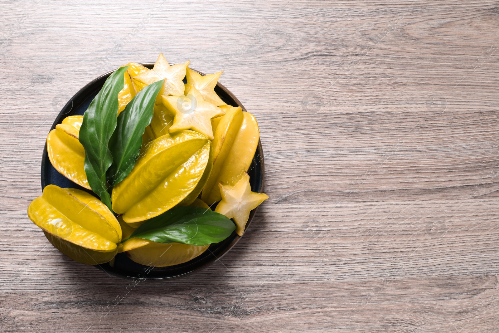 Photo of Delicious carambola fruits on wooden table, top view. Space for text