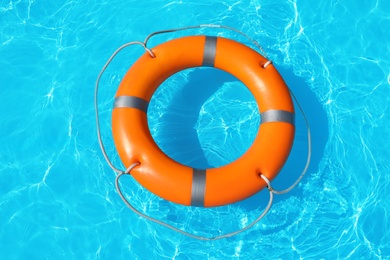 Photo of Lifebuoy floating in swimming pool on sunny day, top view