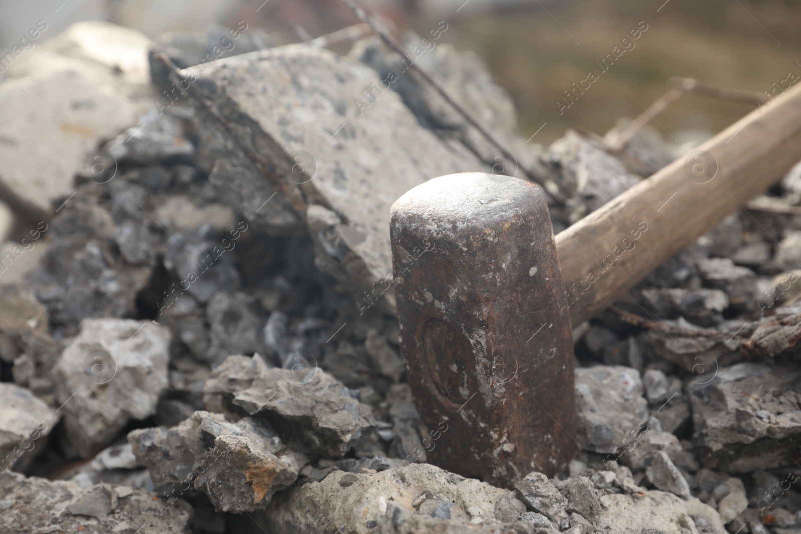 Photo of Sledgehammer on pile of broken stones outdoors, closeup