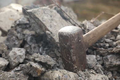 Sledgehammer on pile of broken stones outdoors, closeup