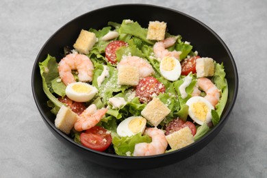 Delicious Caesar salad with shrimps on grey table