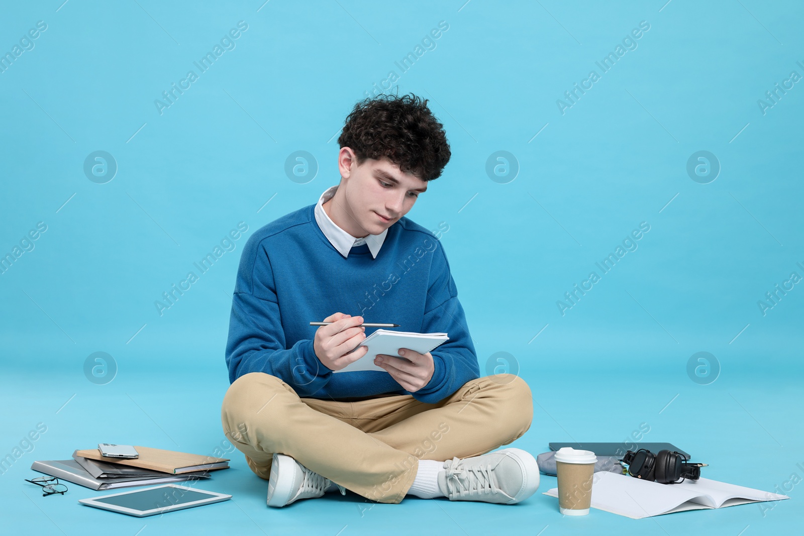 Photo of Portrait of student with notebook and stationery on light blue background