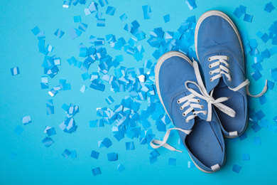 Shoes tied together and confetti on light blue background, flat lay with space for text. April Fool's Day