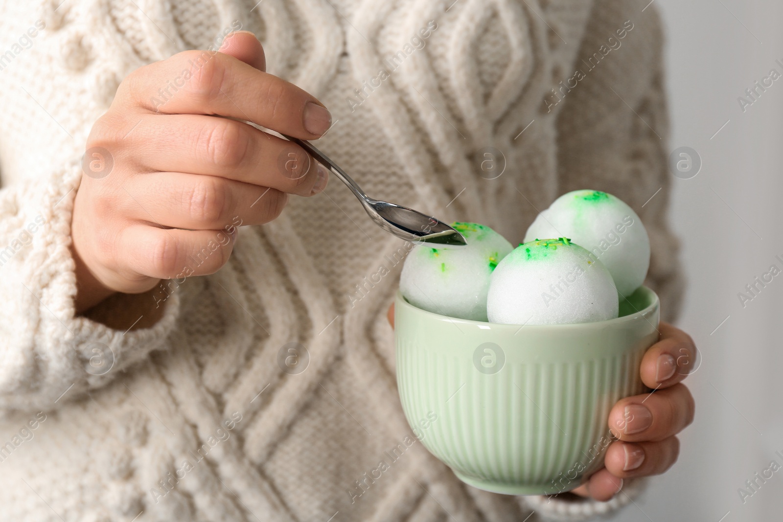 Photo of Woman eating snow ice cream from bowl on light background, closeup