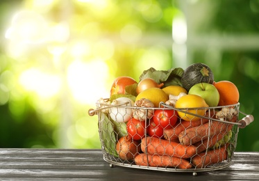 Image of Variety of fresh delicious vegetables and fruits in basket on table against blurred background, space for text