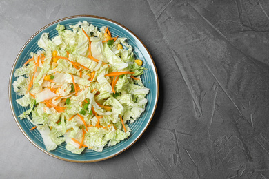 Photo of Plate of fresh cabbage salad with carrot on grey table, top view. Space for text