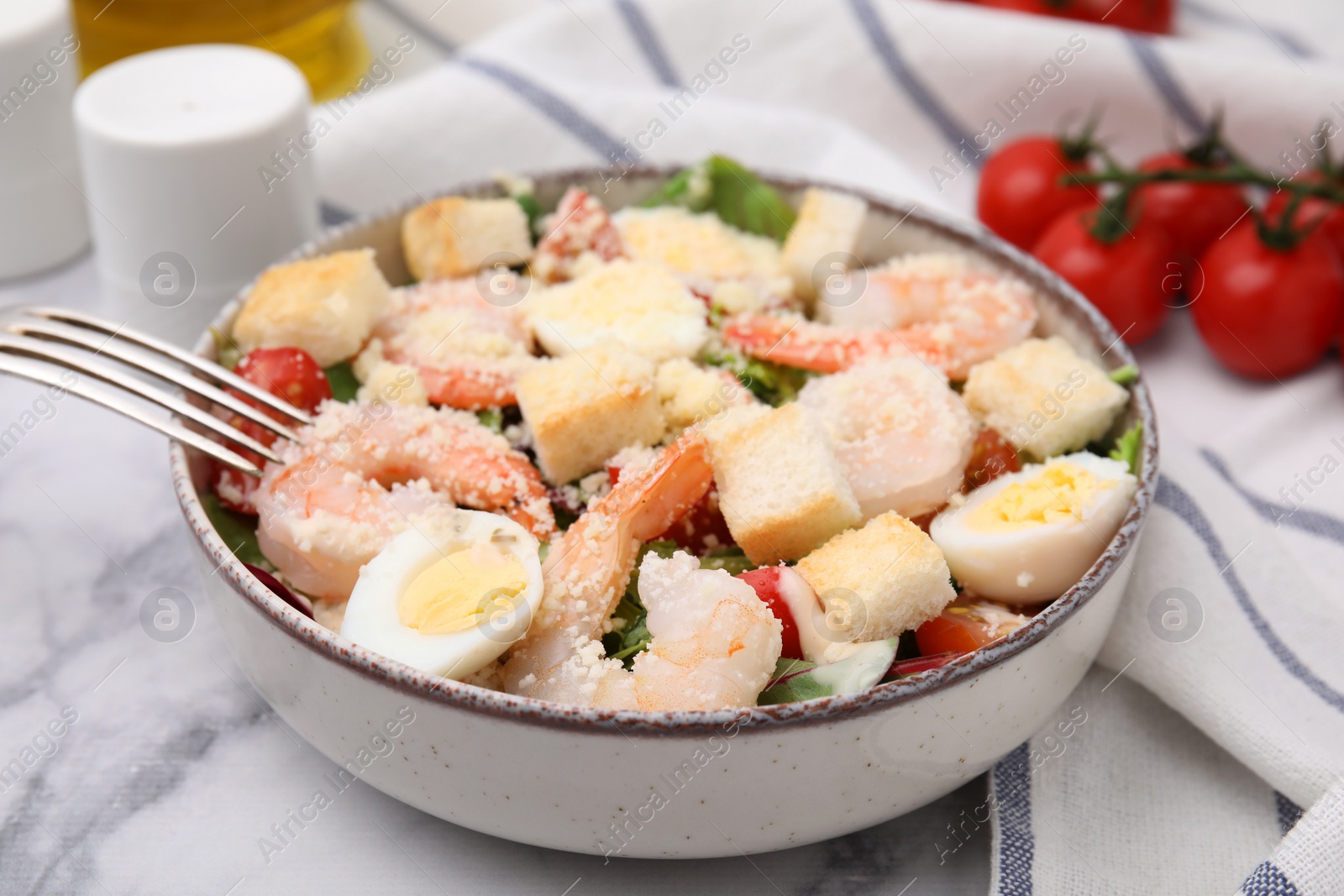 Photo of Delicious Caesar salad with shrimps served on white marble table, closeup