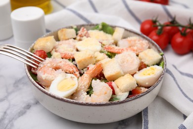 Photo of Delicious Caesar salad with shrimps served on white marble table, closeup