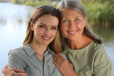Photo of Family portrait of happy mother and daughter spending time together outdoors, closeup