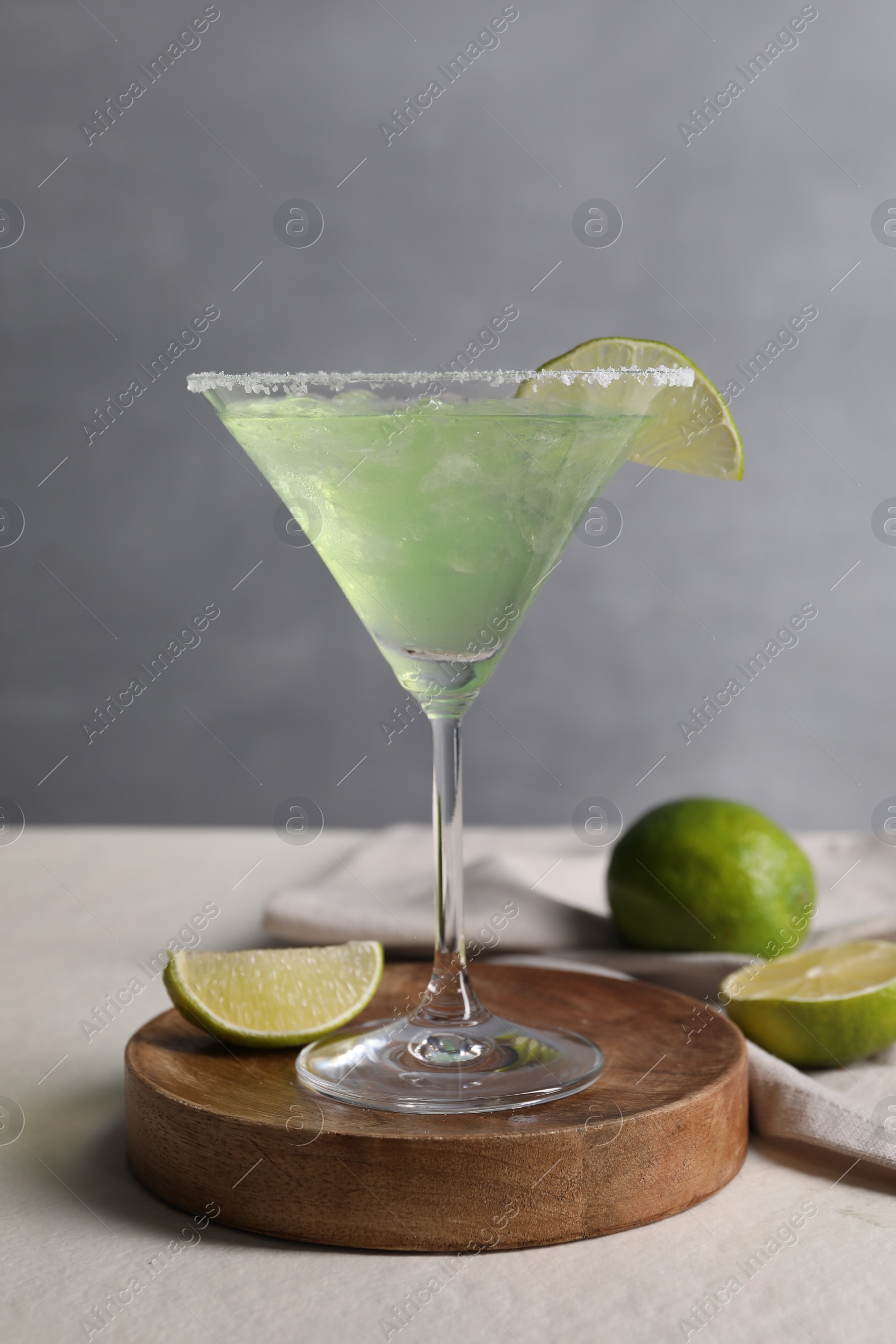 Photo of Delicious Margarita cocktail in glass and limes on light table