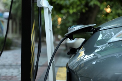 Photo of Charging modern electric car from station outdoors