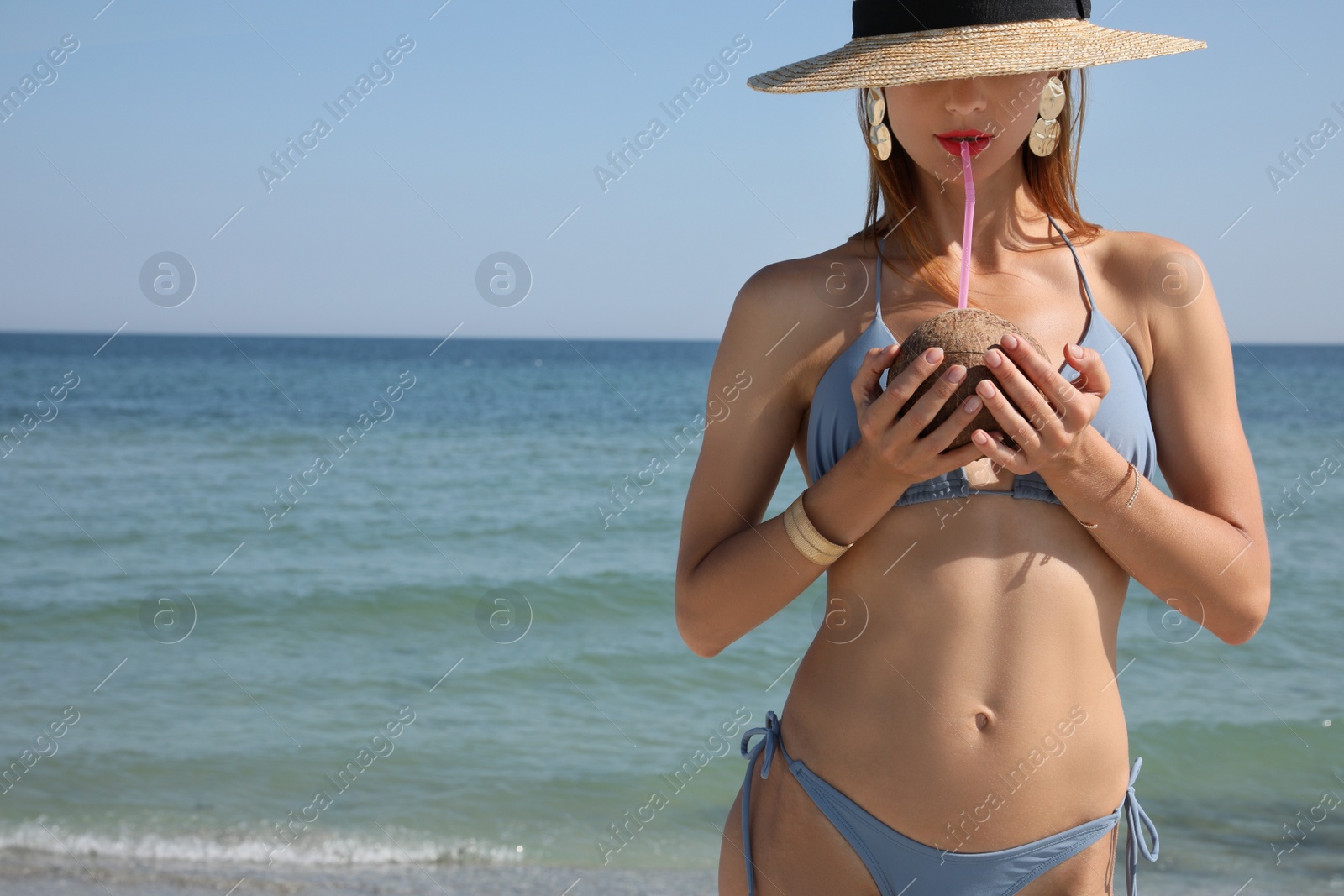 Photo of Attractive woman in bikini drinking exotic cocktail near sea