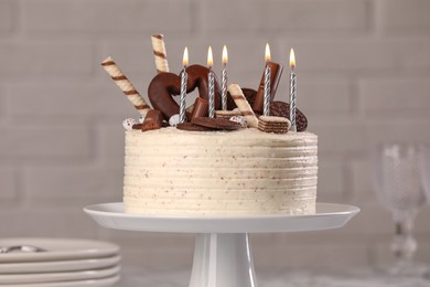 Photo of Delicious cake decorated with sweets and burning candles against blurred background