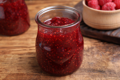 Photo of Delicious raspberry jam on wooden table, closeup