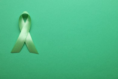 Photo of World Mental Health Day. Green ribbon on color background, top view with space for text