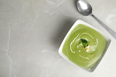 Delicious broccoli cream soup served on grey marble table, flat lay. Space for text