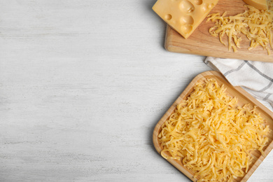 Flat lay composition with grated cheese on white wooden table. Space for text