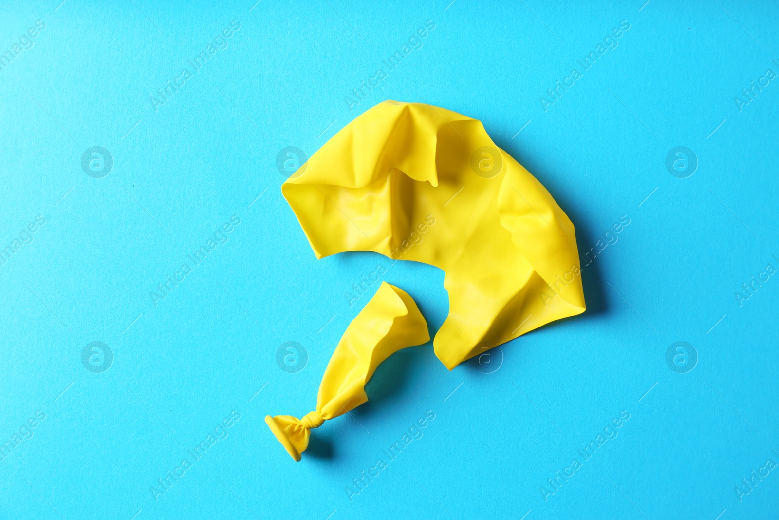 Photo of Popped balloon on color background, top view