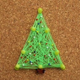 Photo of Christmas tree made of thread and pins on cork board. String art