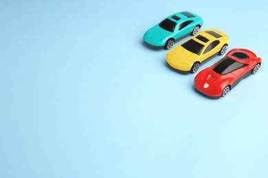 Photo of Different bright cars on light blue background, space for text. Children`s toys