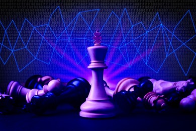 Image of Chess piece among fallen ones on table against background with lines and binary code