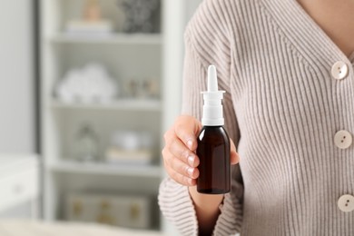 Photo of Woman holding nasal spray indoors, closeup. Space for text