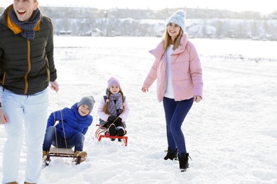 Photo of Happy family with sledge outdoors on winter day