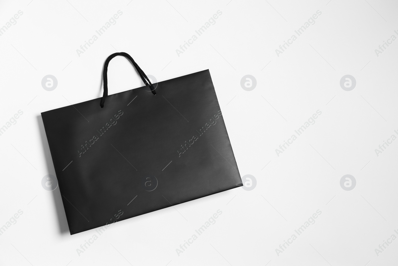 Photo of One black paper shopping bag on white background, top view. Space for text