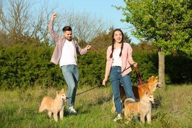 Photo of Young couple with adorable Akita Inu dogs in park