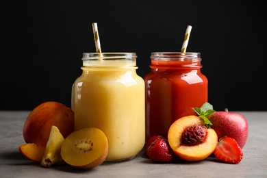 Photo of Delicious juices and fresh ingredients on grey table against black background